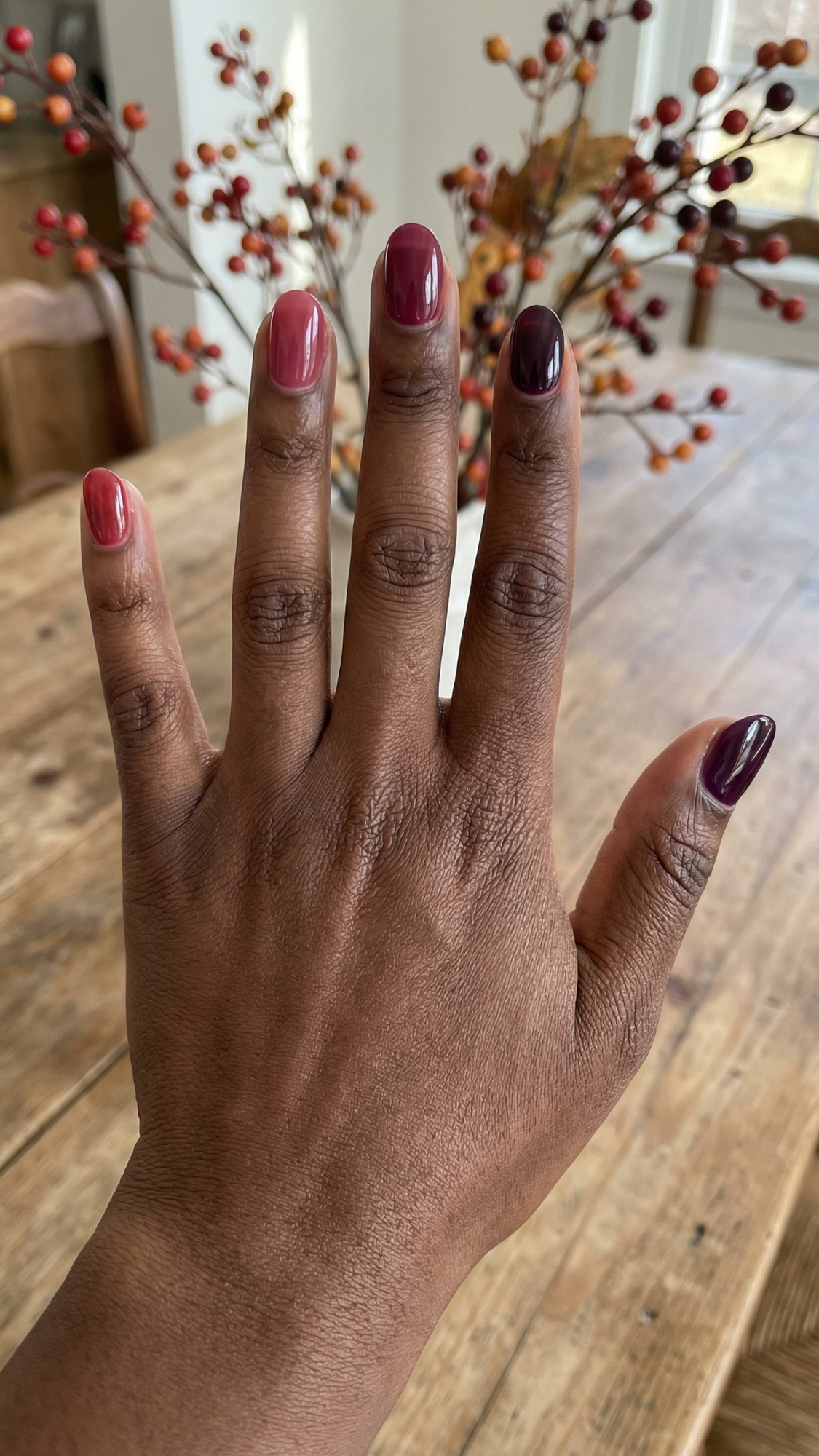 Cranberry Jelly Skittle — “Short oval nails painted in tonal cranberry-to-plum jelly shades, glossy finish, each nail a different berry tone.”
