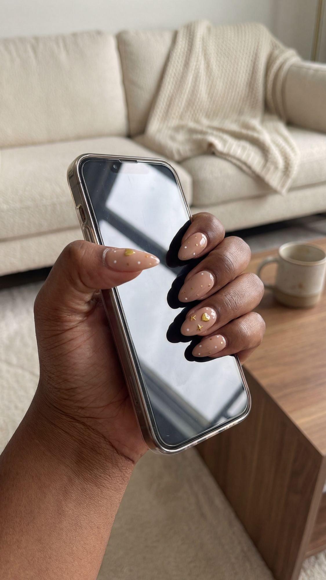 Mismatched Dots & Mini Charms — Almond nails with scattered tiny dot patterns and a couple of flat studs.