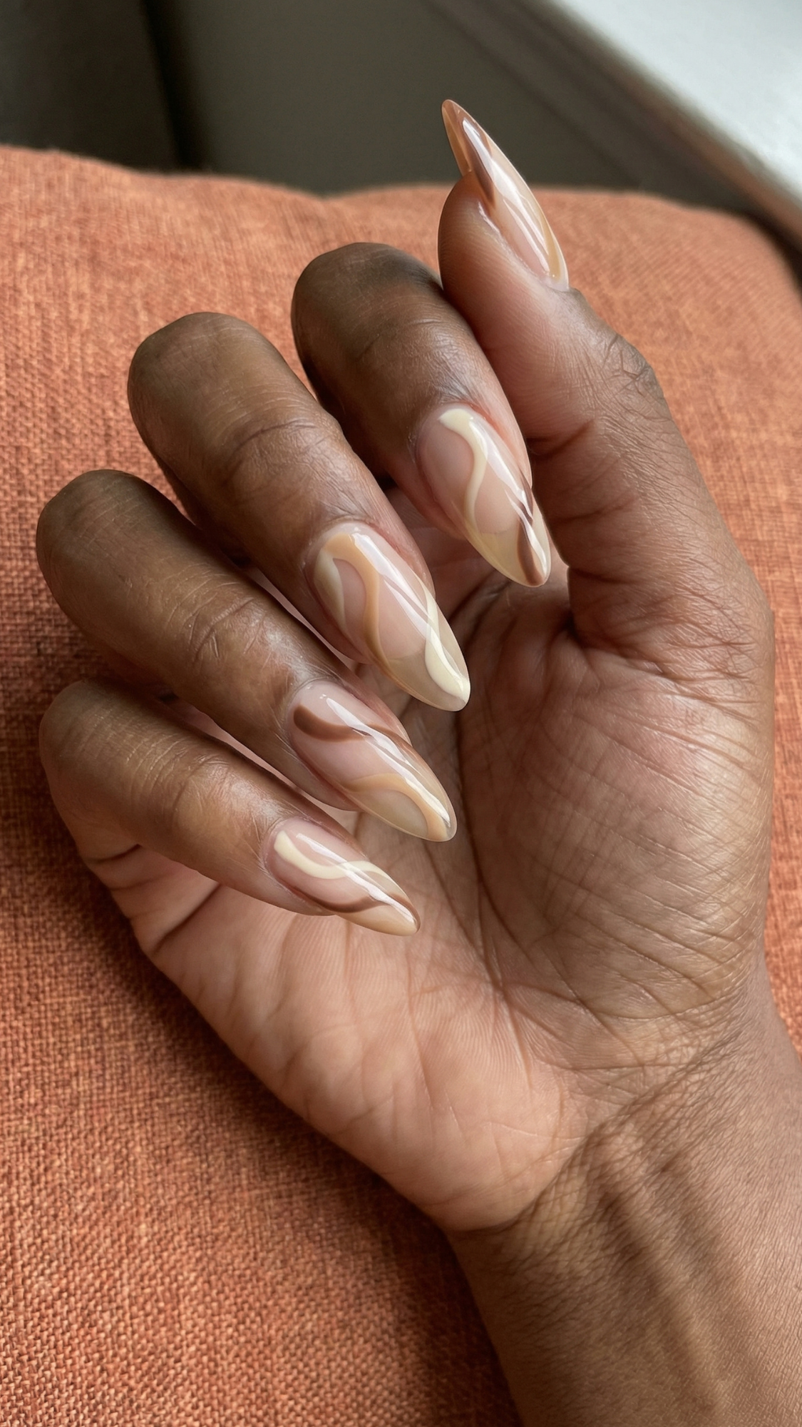 Latte Swirls — “Almond nails with a sheer base and soft marble swirl art in cream, latte, and mocha colors, glossy finish.”
