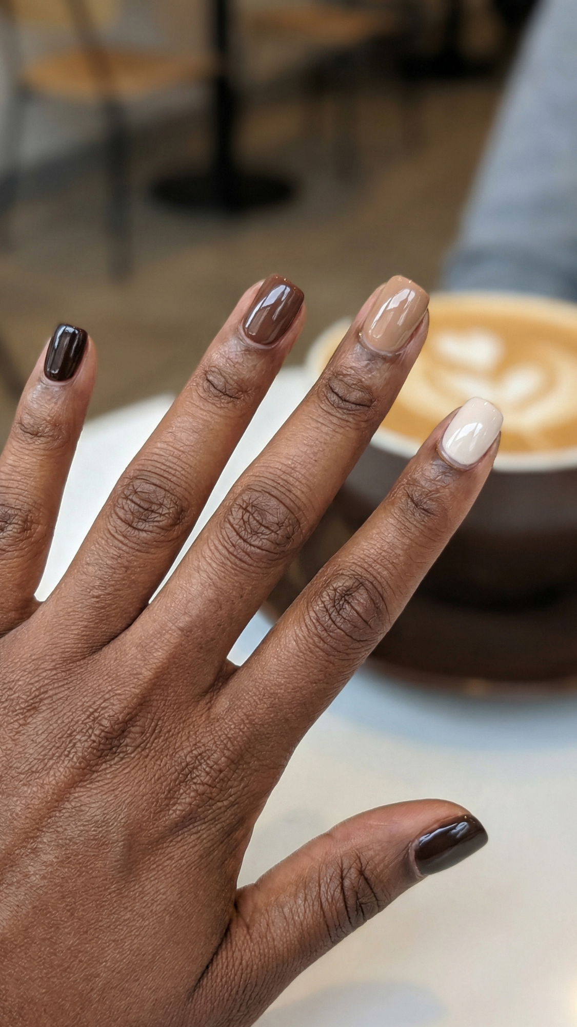 Espresso Skittles (Creams) — “Short squoval nails arranged in gradient shades from oat-milk to deep espresso cream, glossy finish.”
