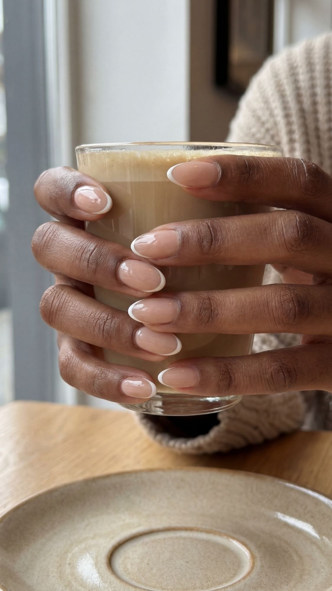 Close-up of almond-shaped nails with ultra-thin micro-French tips hugging the edge over a sheer nude base.