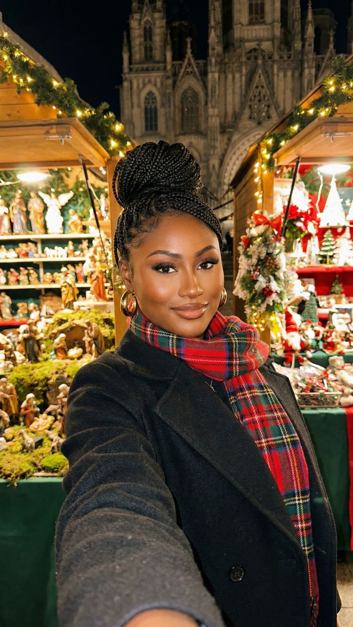 A woman wearing a plaid scarf and dark coat takes a selfie at a festive outdoor Christmas market in cozy Barcelona, surrounded by holiday decorations and nativity figurines, with a cathedral in the background.
