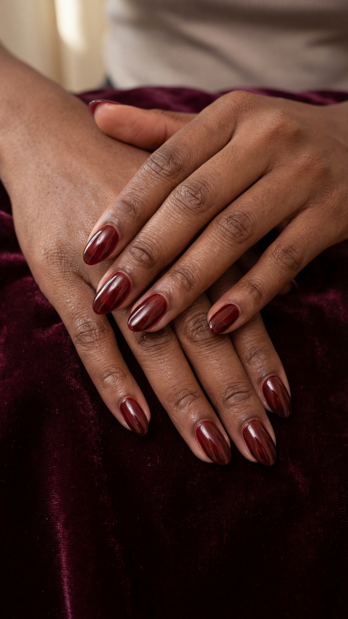 Oxblood Glass — “Short almond nails painted in deep oxblood jelly with a high-gloss finish.”
