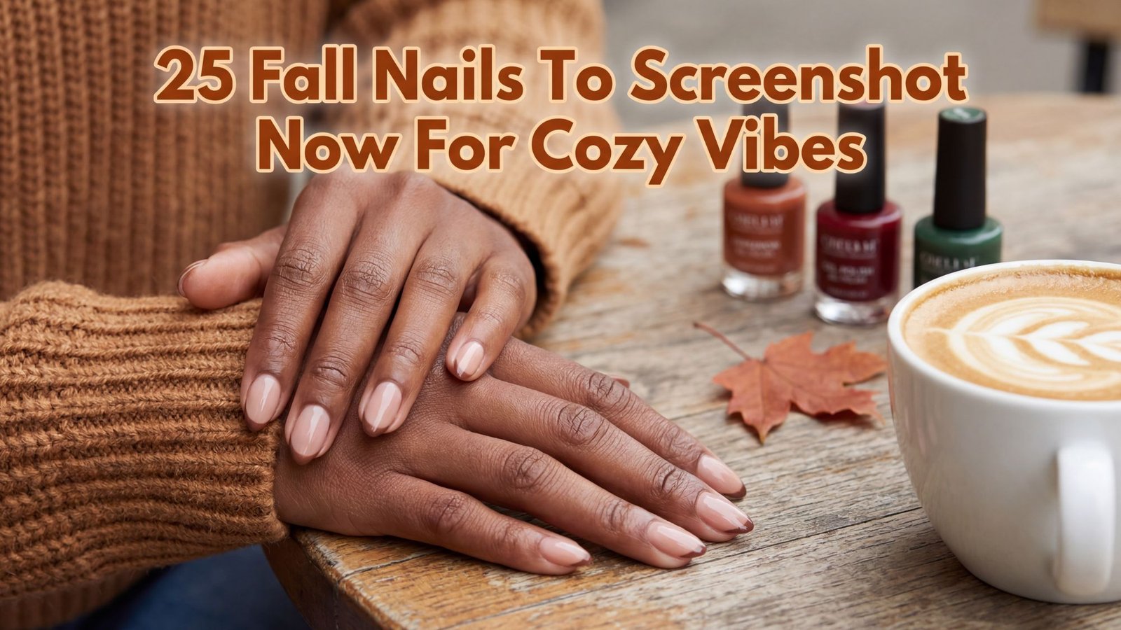 Hands with glossy nude fall manicure resting on a wooden table beside latte art, autumn leaf, and fall-themed nail polish bottles.