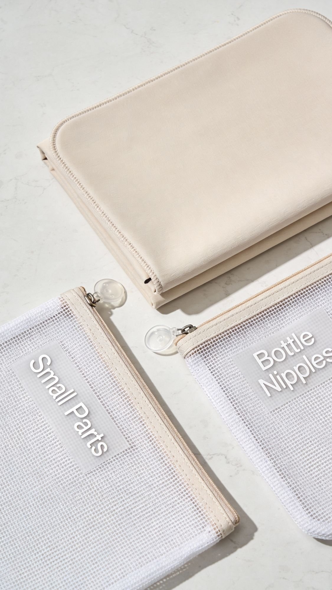 Three pouches lie on a light surface: a large beige zippered pouch and two smaller white mesh pouches labeled “Small Parts” and “Bottle Nipples”—thoughtful choices for useful gifts or gentle gifts for new moms.