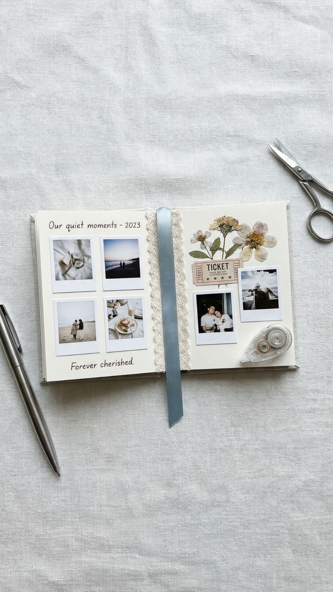 An open scrapbook lies on a light fabric with a pen and scissors nearby—perfect inspiration for easy handmade gifts. The pages display instant photos, pressed flowers, a ticket stub, and a ribbon. Text reads “Our quiet moments – 2023” and “Forever cherished.”.
