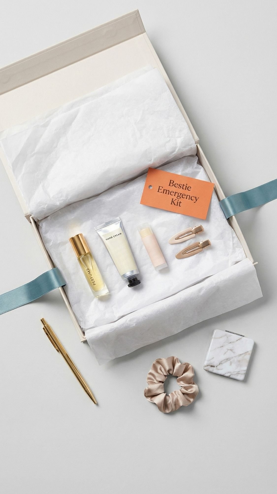 Gift box labeled Bestie Emergency Kit with perfume, lotion, lip balm, hair clips, gold pen, scrunchie, and marble-pattern notepad on a white background—thoughtfully arranged with light blue ribbon; perfect for easy birthday gifts for your best friend.