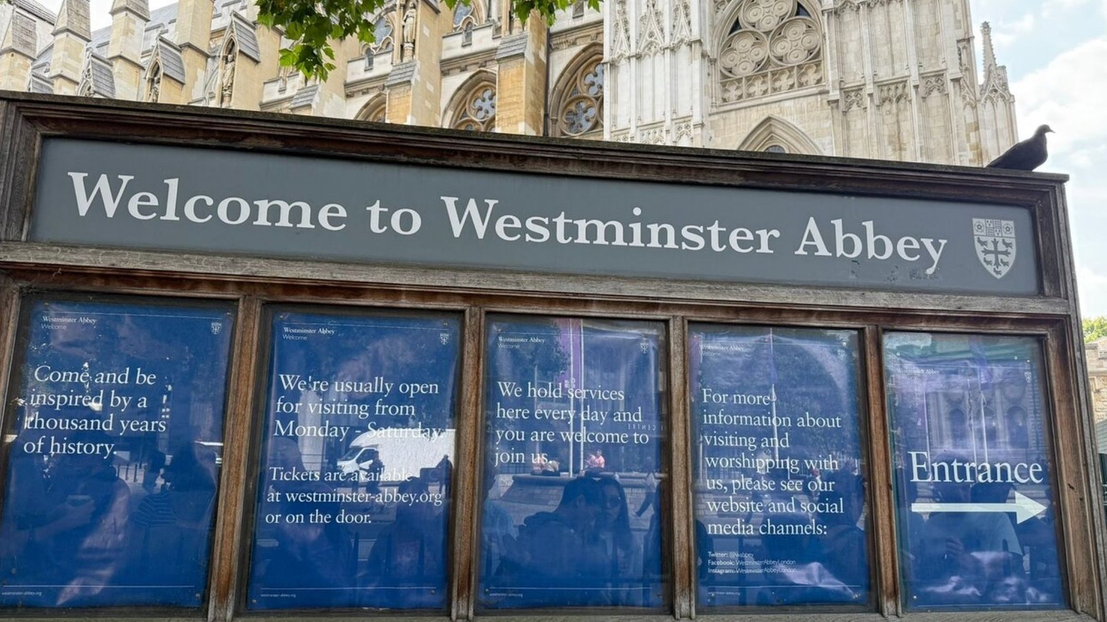 A sign reads Welcome to Westminster Abbey with information panels below about visiting hours, services, tickets, and directions—perfect for anyone planning their London first trip or looking for top London things to do. Westminster Abbey’s exterior is visible in the background.