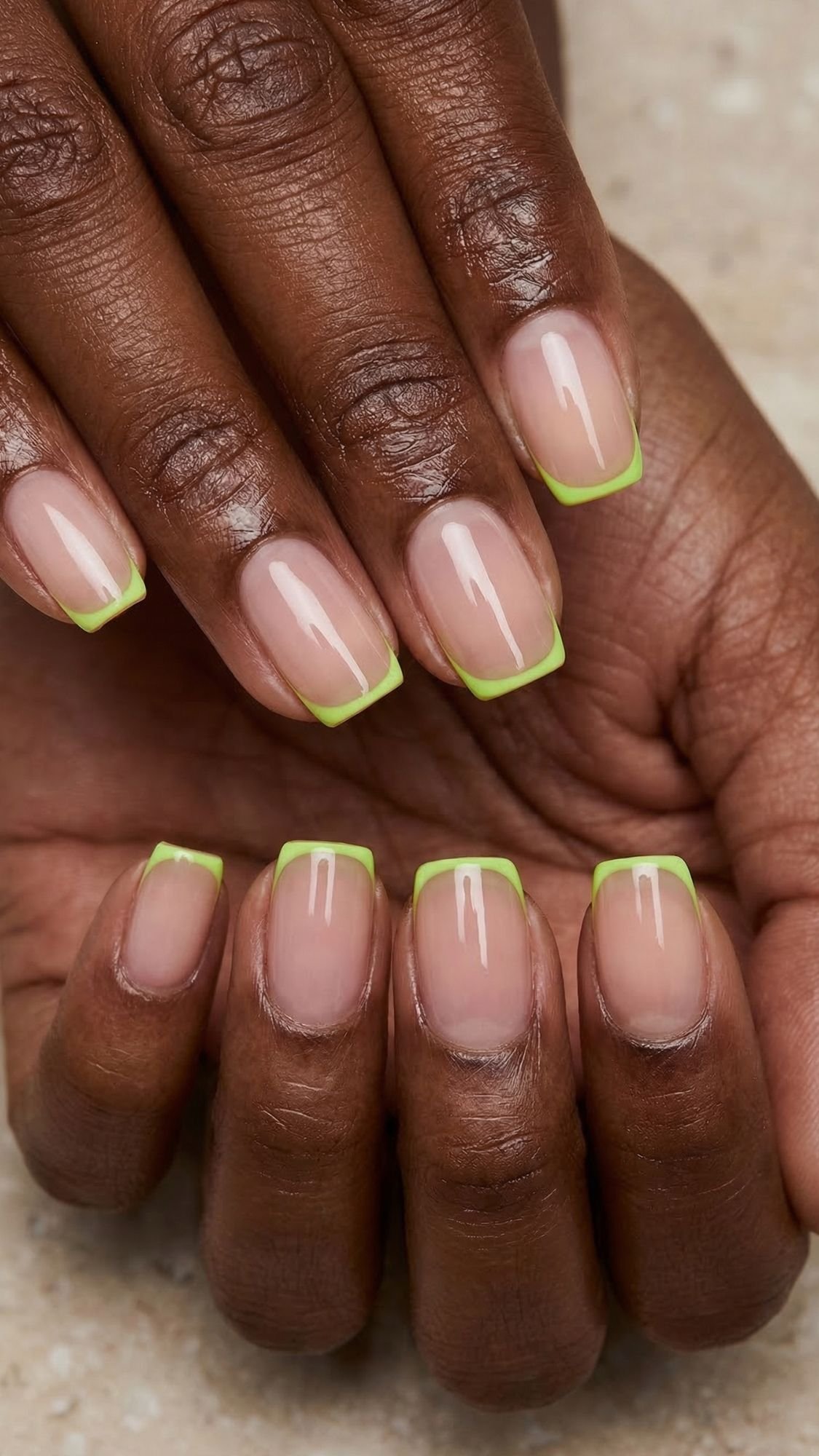 A close-up of hands with manicured nails featuring a natural base color and bright green French tips—perfect for anyone who loves simple nails or wants easy nail designs to try at home. The nails are short to medium length and neatly shaped.