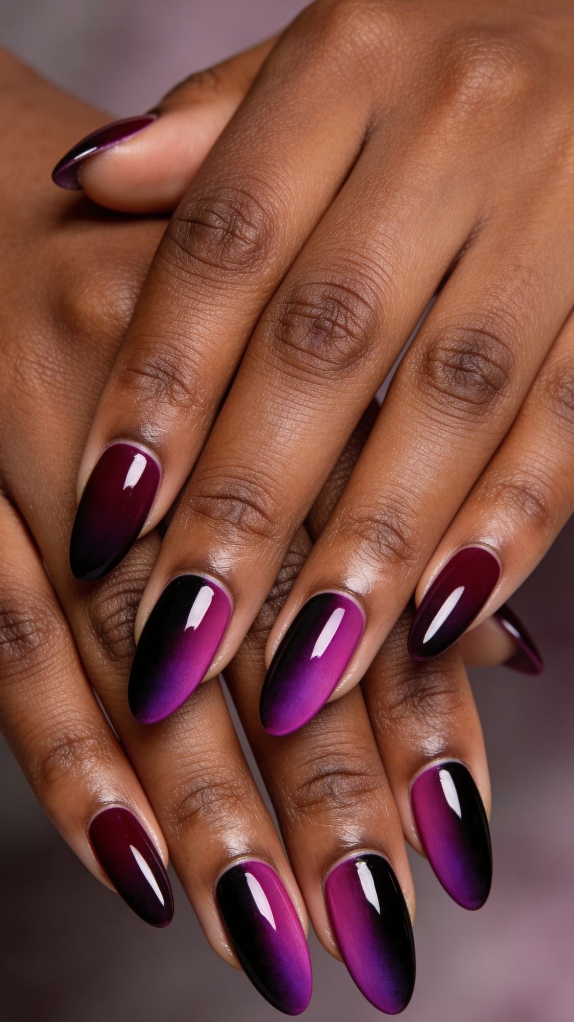 Close-up of hands with almond-shaped nails featuring a glossy purple to black ombre gradient manicure—perfect for easy nail ideas and creating stylish, simple nails at home. The nails are neatly polished and the skin has a smooth, even tone.