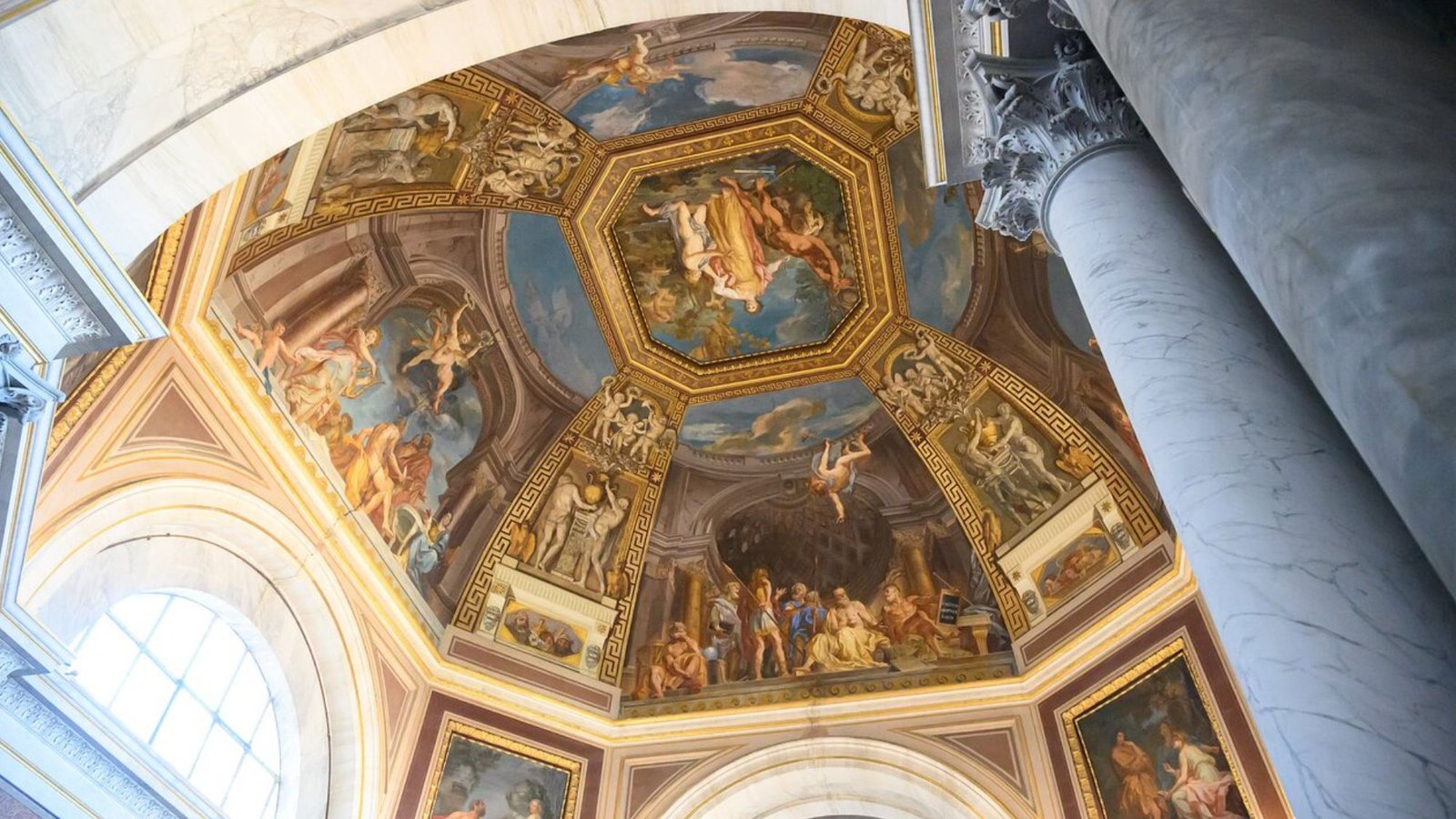 A detailed view of an ornate, domed ceiling decorated with classical-style frescoes—an unforgettable sight for any Italy bucket list—featuring numerous figures and intricate designs, framed by marble columns and arches, with natural light streaming through a nearby window.